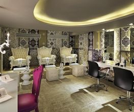 Salón de belleza elegante con sillones y mesas de manicura, decorado en tonos beige y blanco.