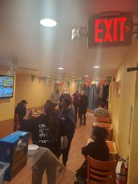 People in a small restaurant with an exit sign.