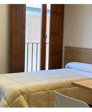 Habitación sencilla con cama individual, escritorio, ventana y decoración en la pared.