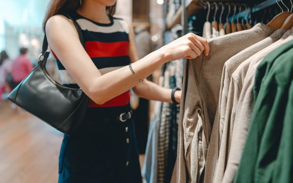 Eine zierliche Frau schaut sich ein Kleidungsstück in einem Mode-Salon an.