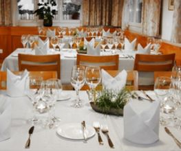 Elegantes Esszimmer mit gedecktem Tisch, weißen Servietten und vielen Gläsern.