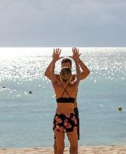 Pareja jugando voleibol en la playa con el mar de fondo.
