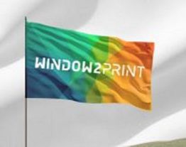 Eine bunte Flagge mit der Aufschrift "WIND0W2PRINT" weht im Wind.