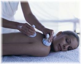 Person erhält entspannende Massage mit Kräuterstempeln auf Rücken.