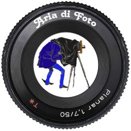 Obiettivo fotografico con disegno di fotografo vintage e testo "Aria di Foto".
