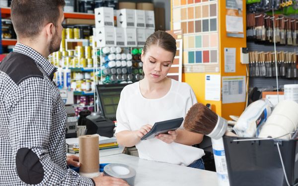 In einem Baumarkt an der Theke findet ein Beratungsgespräch statt.