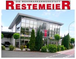 Mehrmarkenwerkstatt Reste meier: modernes Glasgebäude mit Pflanzen umgeben, Passage seitlich.