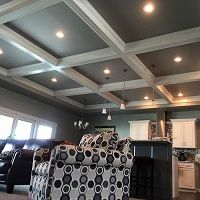 Modern living room with coffered ceiling, recessed lights, and patterned furniture.