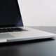 Un laptop aperto su un tavolo nero con schermo spento.