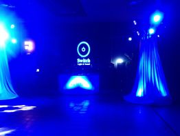 Escena de fiesta con luces azules y pantalla LED con logotipo de encendido.