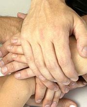 Mehrere Hände, die sich übereinanderlegen, symbolisieren Teamarbeit und Zusammenarbeit.