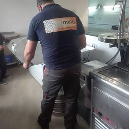 Hombre moviendo un barril metálico en una cocina industrial.