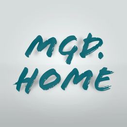 Text in blauer Pinseloptik: "MGD. HOME", auf grauem Hintergrund.