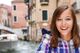 Smiling woman in a plaid shirt with a Venice canal and boat in the background.