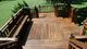 Wooden deck with built-in bench overlooking a green lawn.