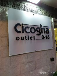 Insegna del negozio "La Cicogna outlet 0-16" su una parete.