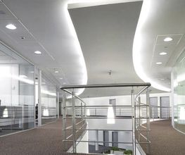 Oficina moderna con pasillo curvo, paredes de cristal y sillas de oficina negras.