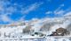 Snowy ski resort with chairlifts and lodge under a bright blue sky.