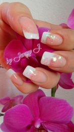 Rosa-weiß manikürte Nägel mit Glitzer, gehalten vor einer violetten Orchideenblüte.