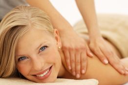 Frau entspannt bei einer Massage mit einem Lächeln auf dem Gesicht.