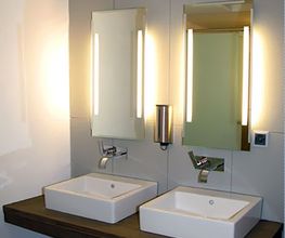 Zwei Waschbecken mit beleuchteten Spiegeln und modernem Design in einem Badezimmer.