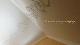 Wandtattoo im Eck mit floralem Design, helle Holzböden und Schriftzug „Hammer Raumdesign“.