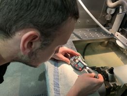 Mann misst präzise ein Metallteil mit einer digitalen Schieblehre.