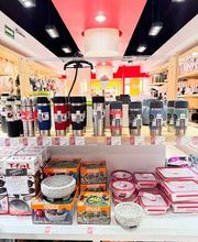 Tienda con termos, tazones y envases en estantes blancos, iluminada y organizada.