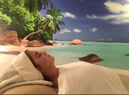 Vrouw ontspant bij tropisch strand met palmbomen en turquoise zee, liggend op een handdoek.