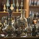 Collection of ornate, intricately designed metal vases and ornate jugs on wooden shelves.