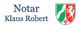 Text: "Notar Klaus Robert" neben einem Wappen mit grünem, weißem und rotem Löwen.