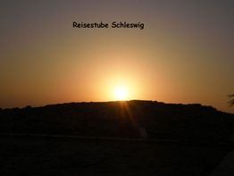 Sonnenuntergang über einem Hügel mit dem Schriftzug "Reisestube Schleswig" am Himmel.