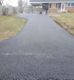 Newly paved asphalt driveway leading to a house with a single person in the distance.