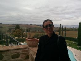 Donna con occhiali da sole davanti a un paesaggio collinare.