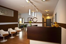 Moderne Rezeption mit braun-weißen Möbeln, Pflanzen und stilvollen Pendelleuchten.