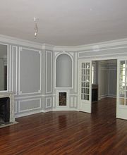 Leerer Raum mit Kamin, grauen Wänden, Holzfußboden und Doppeltüren.