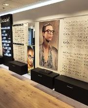 Optiekwinkel met brillen op display en grote foto's van gemodelleerde brillen aan de muur.