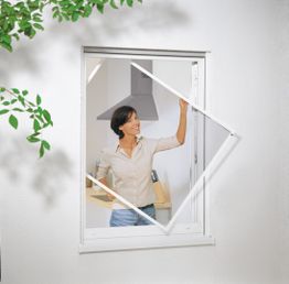 Frau öffnet ein Insektennetz an einem Fenster. Draußen sind Blätter zu sehen.