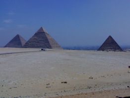 Drei Pyramiden stehen in der Wüste unter klarem Himmel.