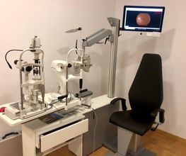 Consultorio de oftalmología con maquinaria y pantalla mostrando imagen ocular.