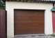 Brown garage door with horizontal panels in a light-colored structure.