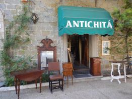 Ingresso di un negozio di antiquariato con mobili antichi esposti all'esterno.