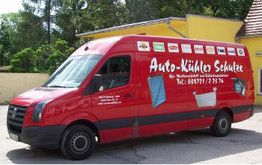 Roter Lieferwagen mit "Auto-Kühler Schultz" und Kühlermotiven, geparkt vor gelber Wand.