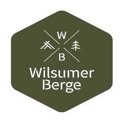 Grünes Logo mit Schriftzug "Wilsumer Berge", zwei Symbolen und den Buchstaben W und B.
