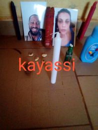 Photographies, bougies colorées, coquillages et flacon, disposés sur le sol avec le mot "kayassi".