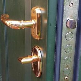 Tür mit goldfarbenen Griffen und sichtbarem Schlossmechanismus.