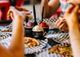 People enjoying pizza and ice cream at a table with black and white checkered paper.