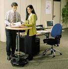 Zwei Personen stehen an einem Stehtisch im Büro und schauen sich gemeinsam Dokumente an.