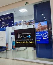 Fachada de uma casa de câmbio com propagandas de envio de dinheiro e serviços de câmbio.