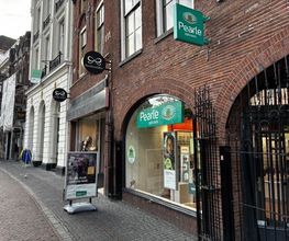 Winkelstraat met Pearle opticien en andere winkels in een rij, bakstenen panden.